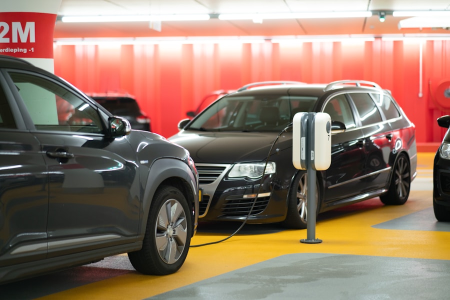 Electric car plugged into a charging station between parked cars in an underground garage