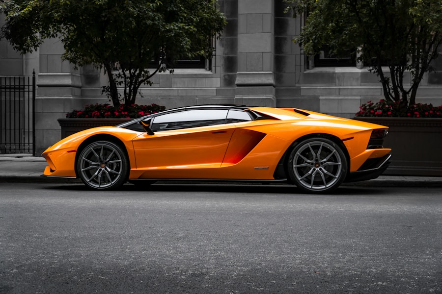 Orange low-slung sports car parked on a city street beside a stone building