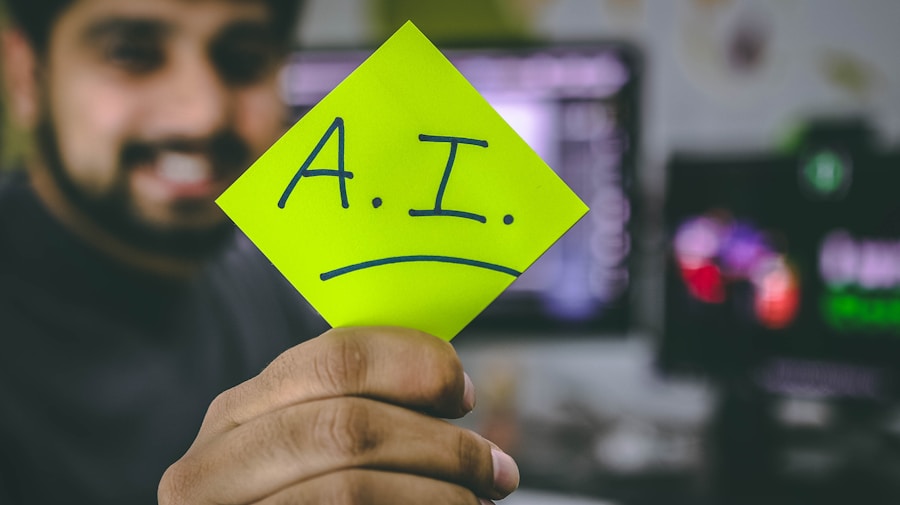 Person holding a neon green note labeled “A.I.” with a sad face in a computer workspace